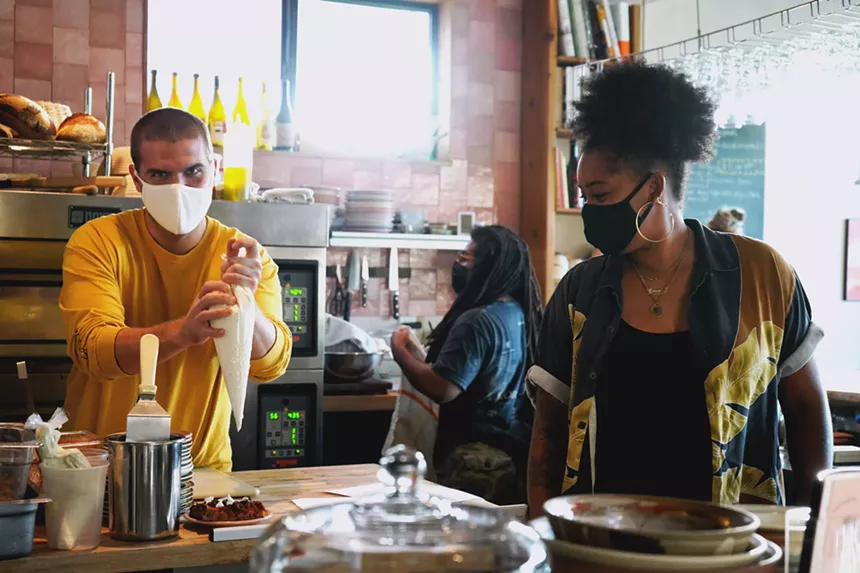 Two restaurant owners holding a frosting piping bag