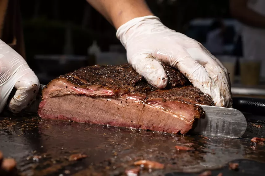 A man slice meat with a white latex glove