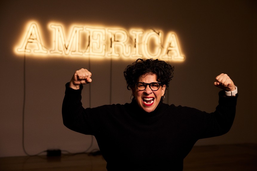 Carmen Pelaez stands in front of a light-up sign spelling out "America"