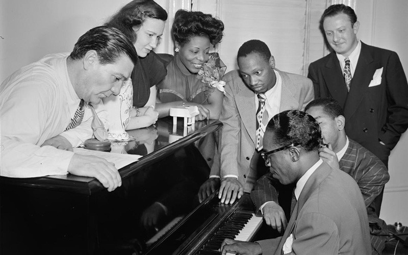 Black and white photo of Jack Teagarden, Dixie Bailey, Mary Lou Williams, Tadd Dameron, Hank Jones, Dizzy Gillespie, and Milt Orent