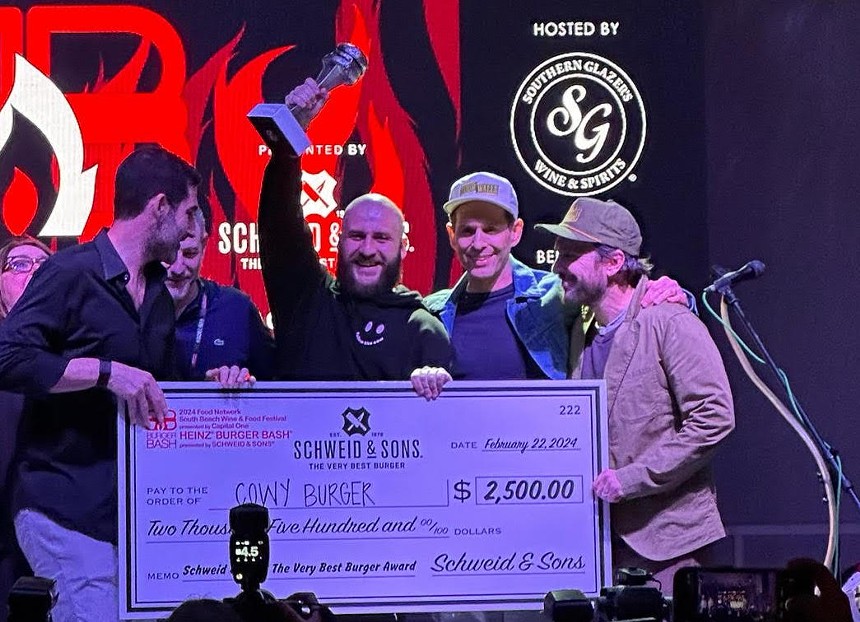 Men on stage holding a check and a trophy