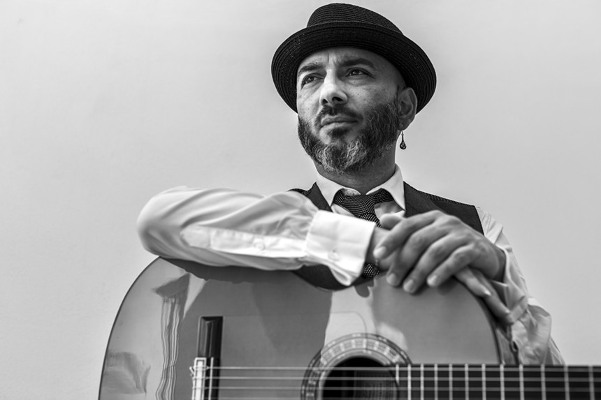 Black and white image of Rycardo Moreno with his guitar on his lap