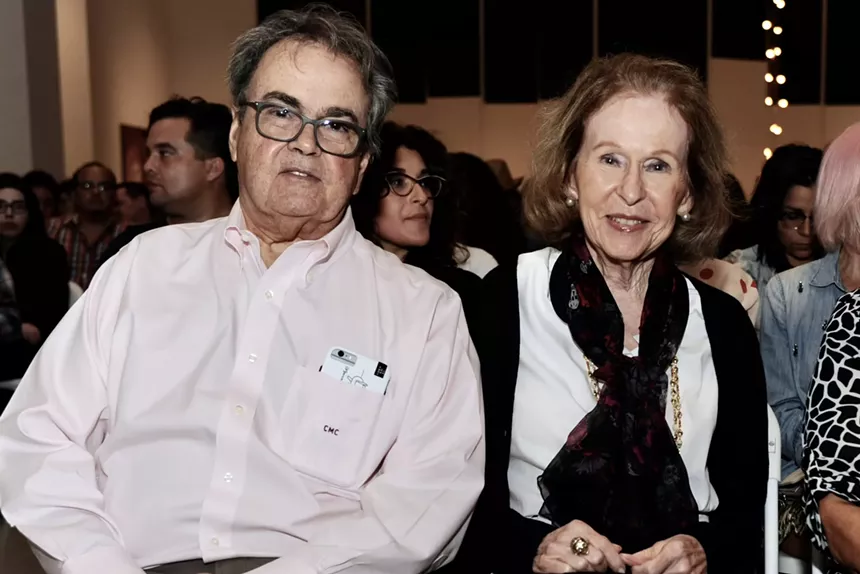 Carlos and Rosa de la Cruz seated down and starting at the camera