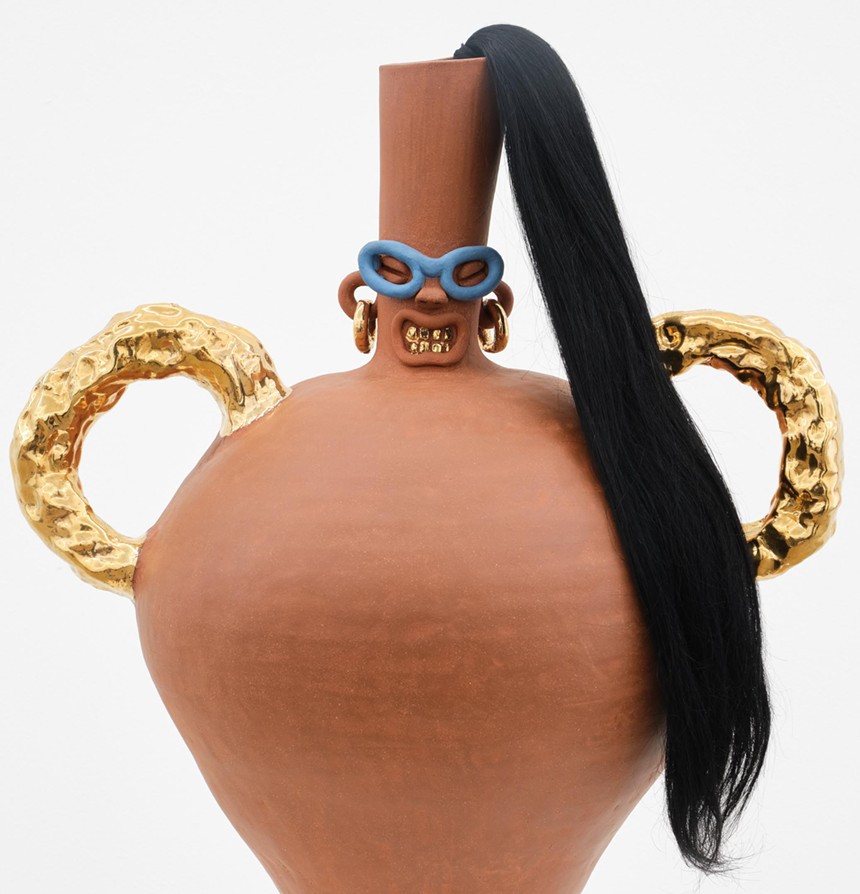 A terracotta jug with a wig and a painted face