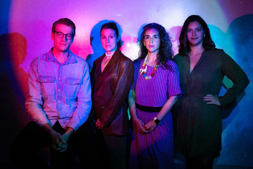Tim Davis, Elizabeth Price, Vanessa Garcia, and Victoria Collado standing against a wall with color lights