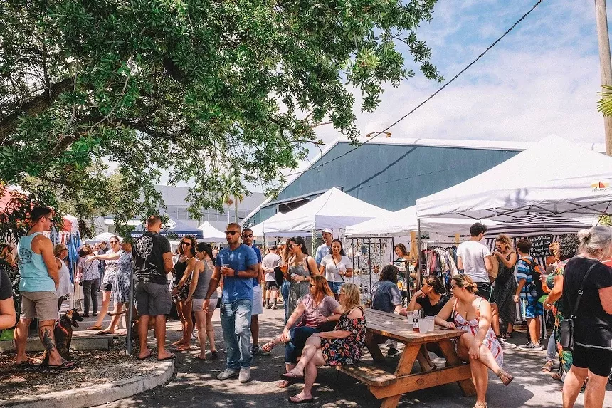 a group of people sitting at picnic tables at the farmers market