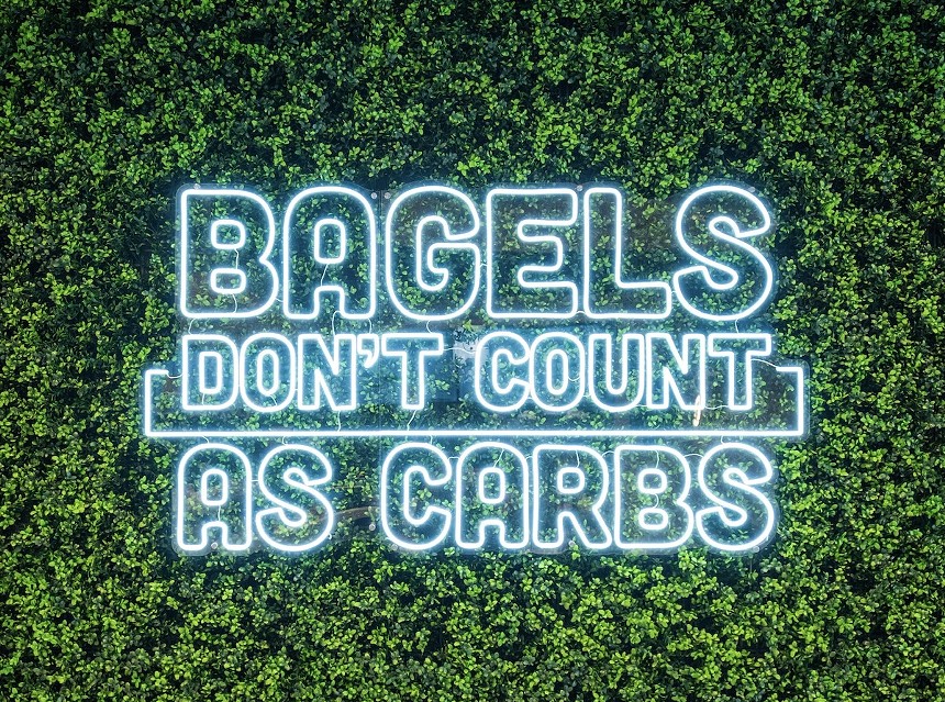 a bright "Bagels Don't Count as Carbs" neon sign.