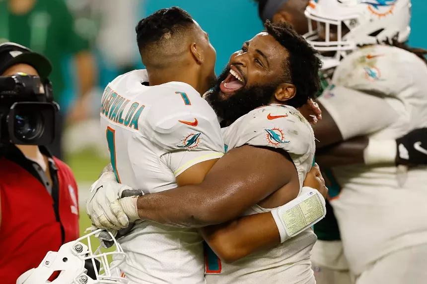 NFL defensive tackle Christian Wilkins smiles wide and hugs quarterback Tua Tagovailoa