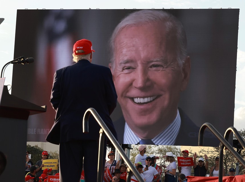 Donald Trump stares at a large screen with Joe Biden's face displayed on it