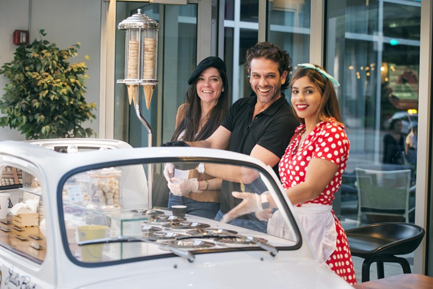 Three people serving ice cream from a car