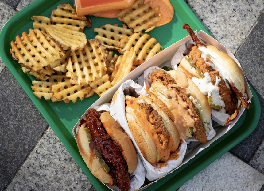 Four sandwiches next to waffle fries
