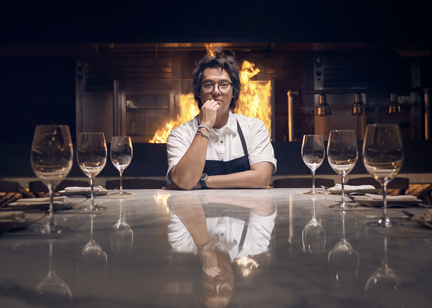 A man sitting across from a fireplace surrounded by empty wine glasses