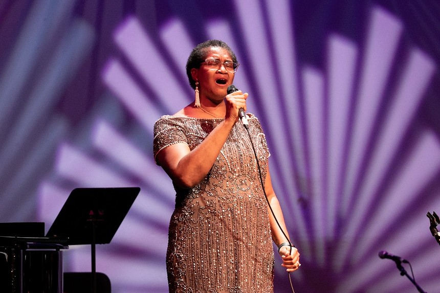 Yvette Norwood singing into a microphone in a sequined dress