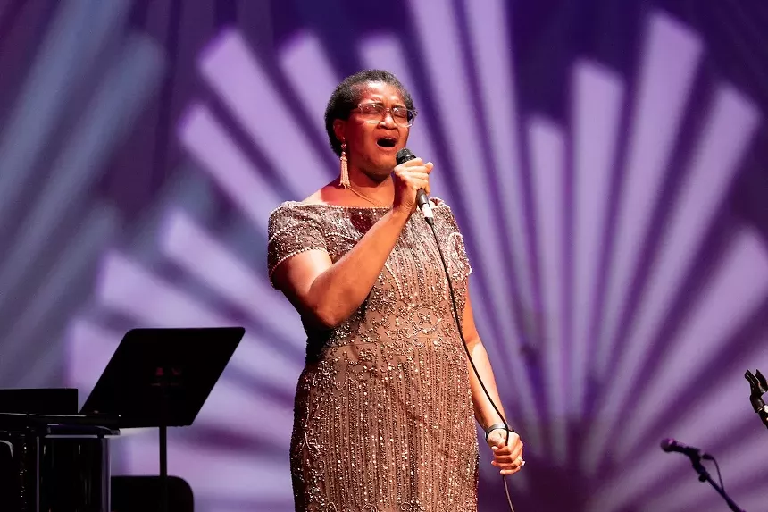 Yvette Norwood singing into a microphone in a sequined dress