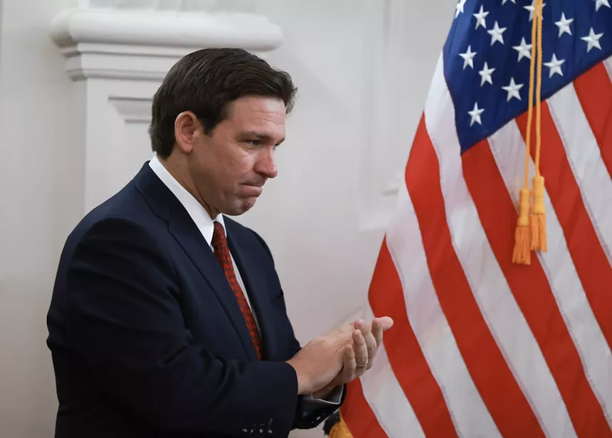 Florida Gov. Ron DeSantis puckers his lips at a press conference