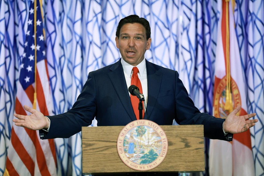 Florida Gov. Ron DeSantis at a podium with his arms spread out