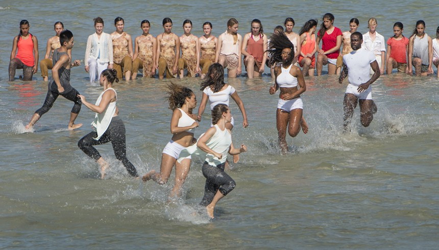 Dancers dressed in white running around shallow water