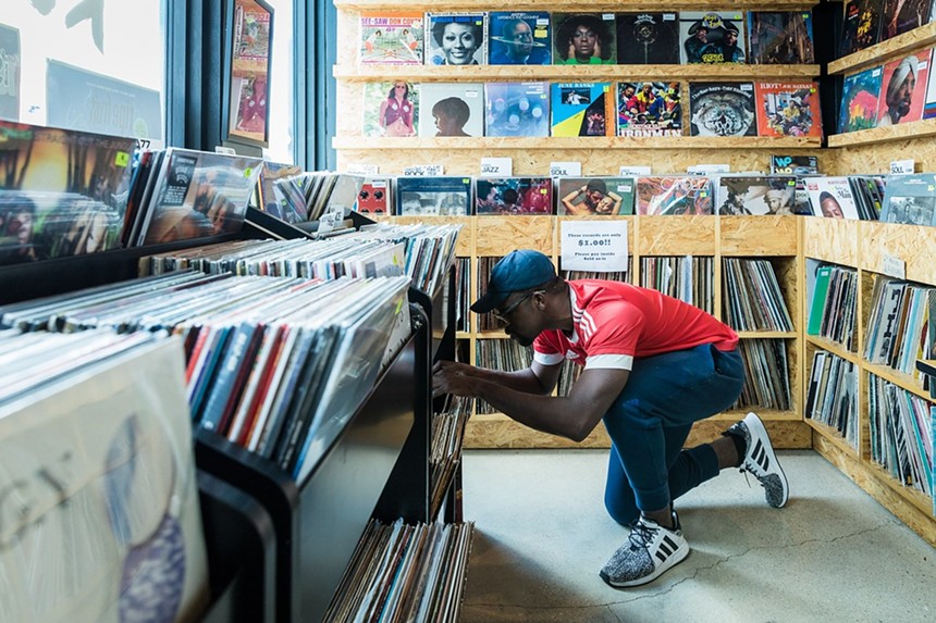 A man crouching down as he searches through crates of records at Lucky Records