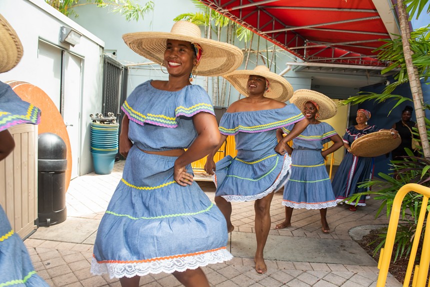 Women dancing in blue dresses and straw hats