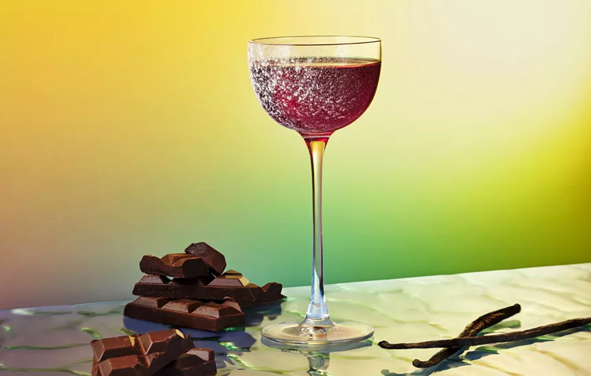 red cocktail in glass with green background