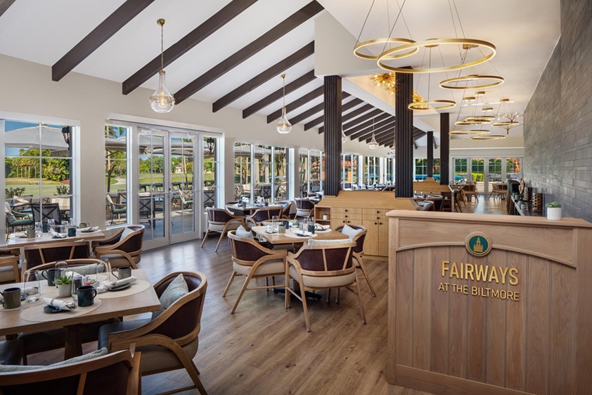 A wooden dining room with large windows and round chandeliers