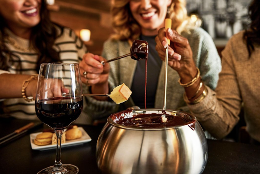 Three women eating chocolate fondue from the Melting Pot.