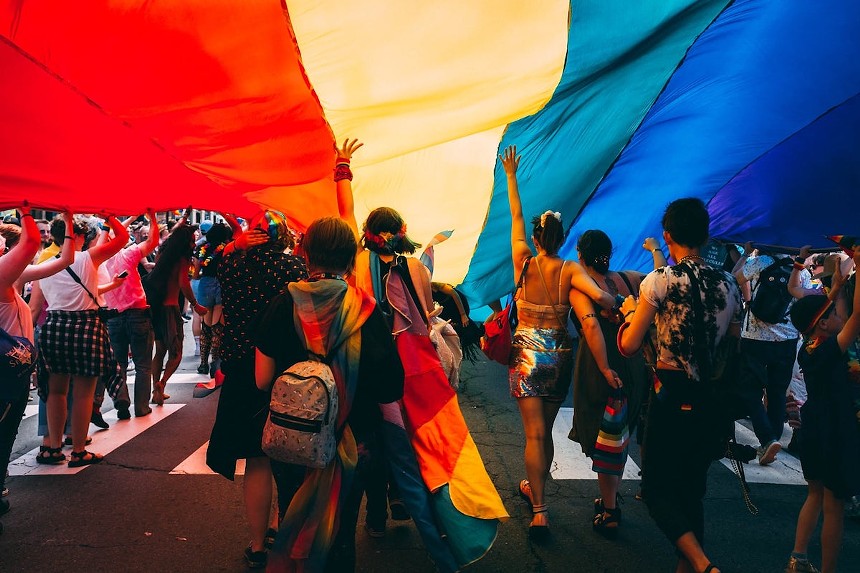 People walking under a rainbow flag