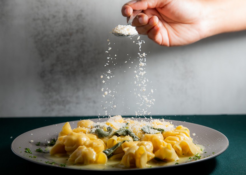 Pasta being tossed with cheese