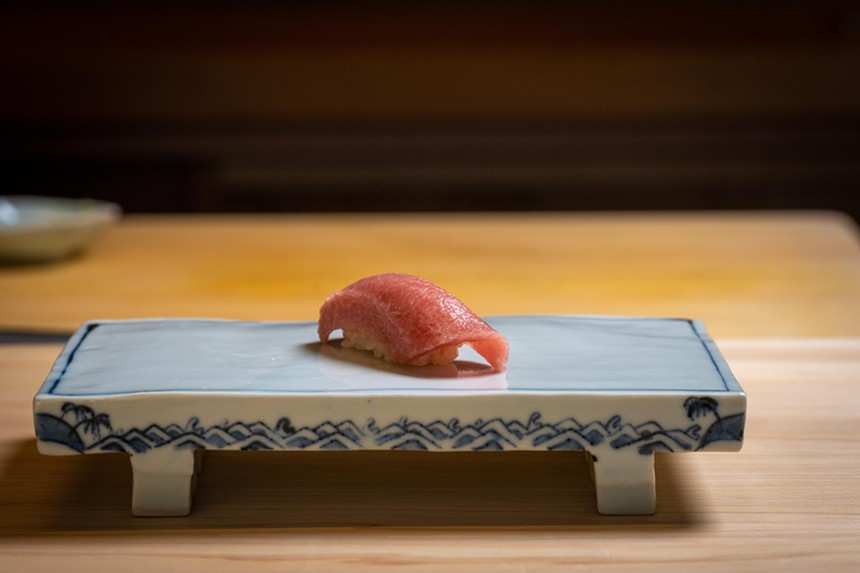 A piece of sushi on a light blue platter on a wooden table