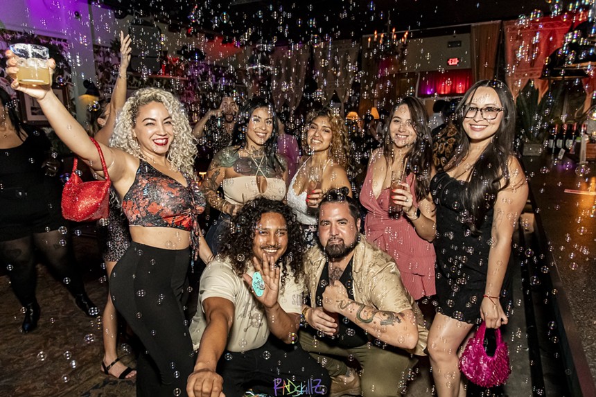 A group of people posing for the camera as bubbles float in the air at Curfew Club