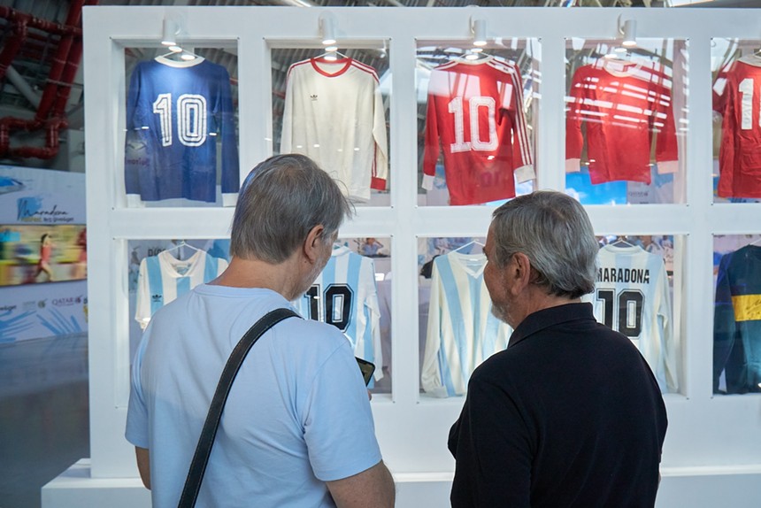 Two men looking at a display of Diego Maradona's soccer jerseys