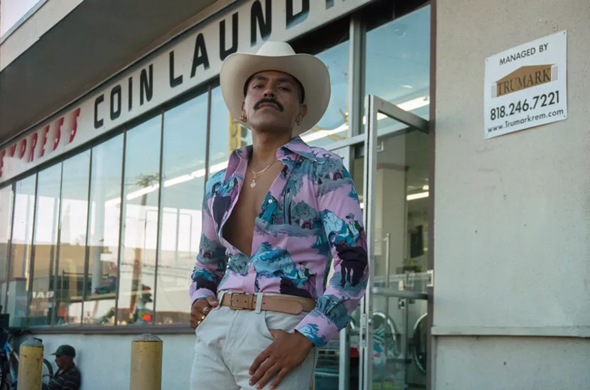 A ranchero poses in front of a laundromat.