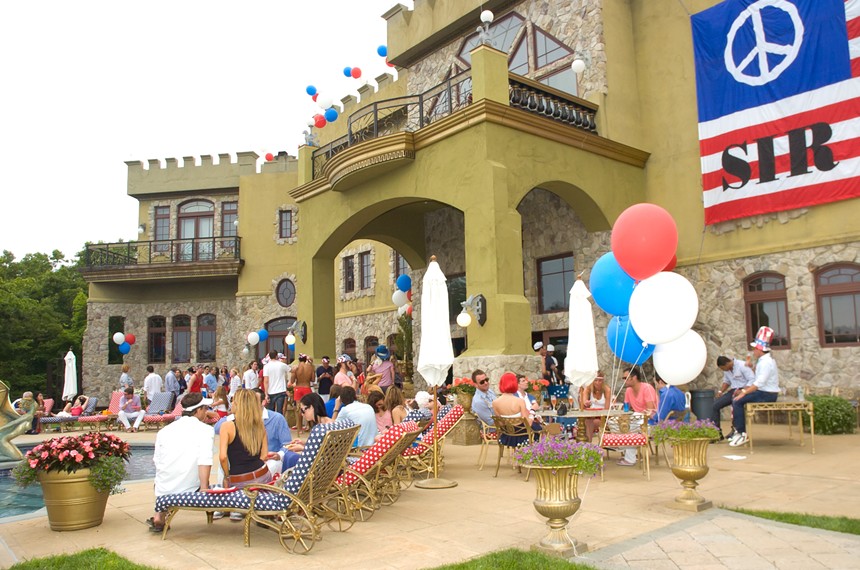 Patriotic red-white-and-blue banners and balloons adorn a large castle-like house in New York