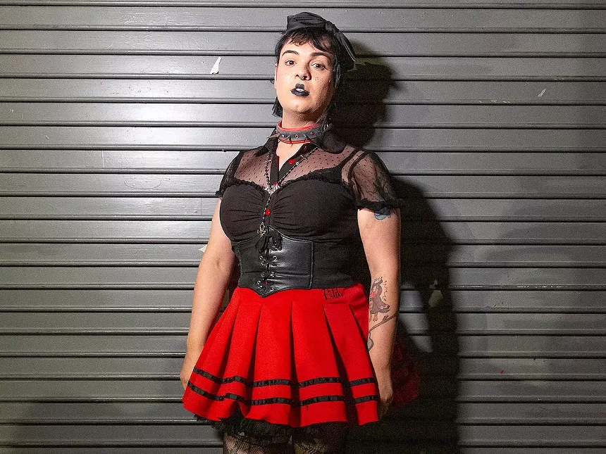 Day Yera in a black top and red skirt