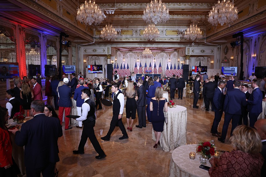 An election night gala inside Mar-a-Lago meeting room. Chandeliers dangle over a crowd dressed in suiits