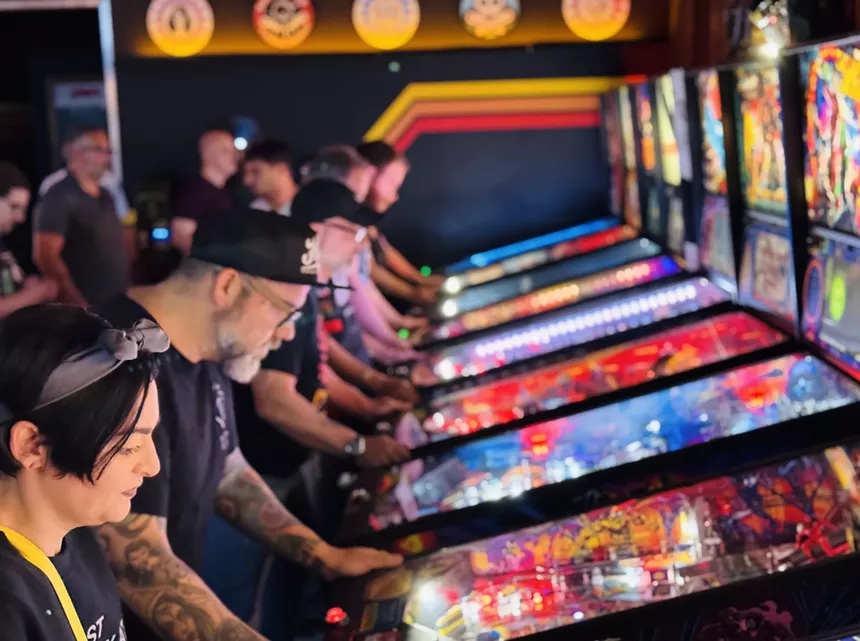 A row of people playing pinball machines at Satellite Pinball Lounge