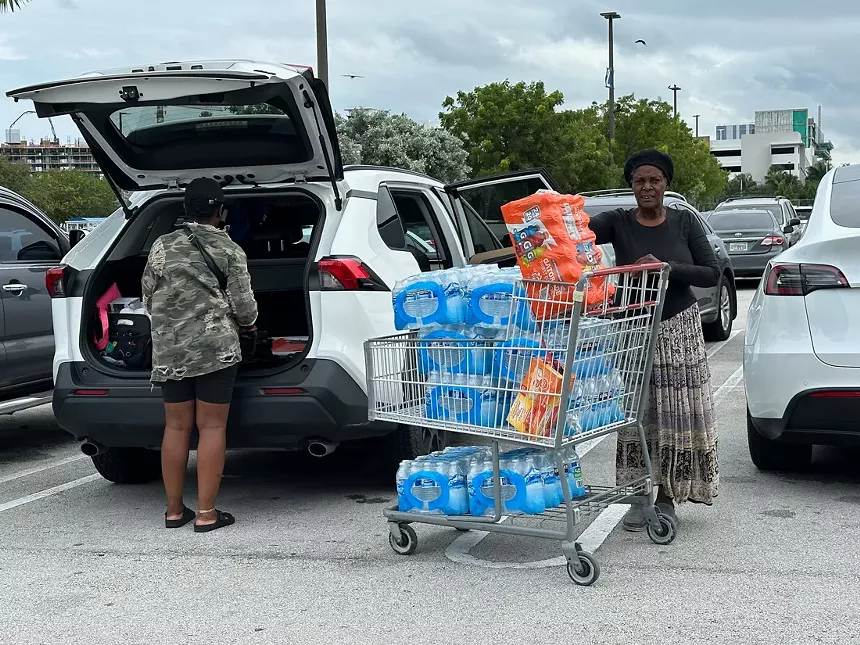 A woman loads up her car with cases of water.