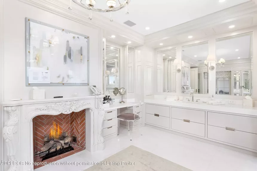 Spa-like master bathroom with a marble fireplace, custom vanity, and white decor