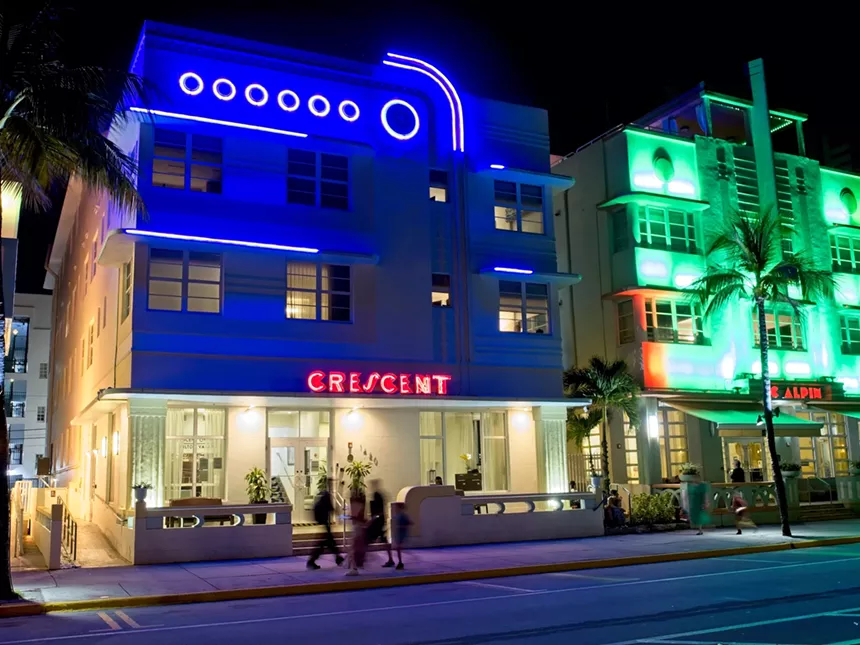 Exterior of the Crescent Hotel in Miami Beach at night with neon lights lit up
