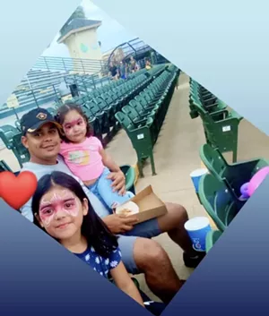 A man poses with his two young daughters.