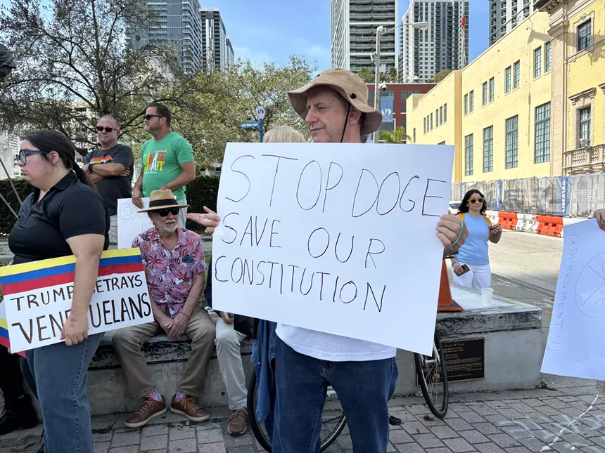 A protester holds a sign, "Stop DOGE, Save Our Constitution."