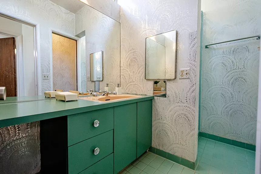 A green bathroom with white and silver wallpaper