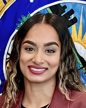 headshot of a woman in front of a colorful flag