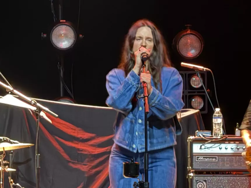 a woman dressed in blue, singing into a microphone