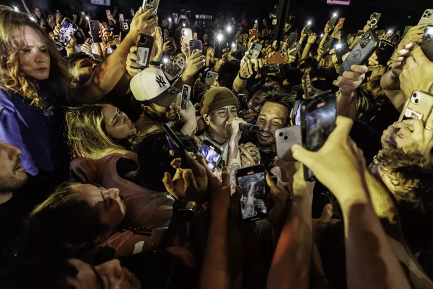 fans holding phones swarm a rapper