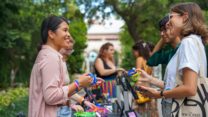 people trade multicolored bracelets at a Pride Month event
