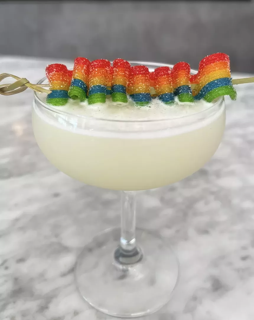 a white cocktail topped with a rainbow-colored gummy