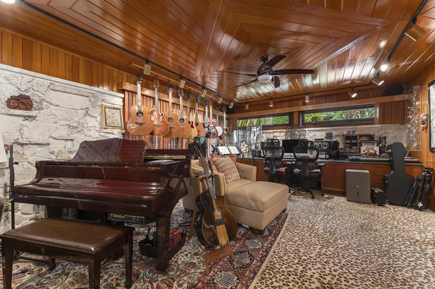Music studio with a piano and acoustic guitars hanging on the walls