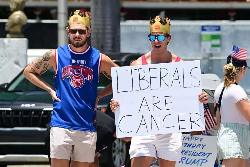 Two men in Burger King hats hold a sign reading, "Liberals are cancer."
