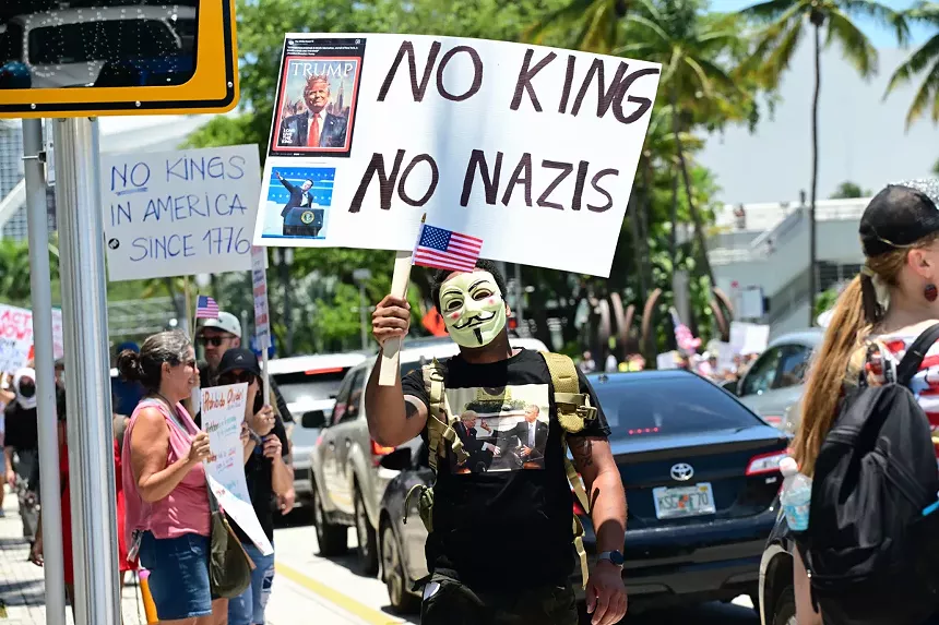 A masked man demonstrates against President Donald Trump.